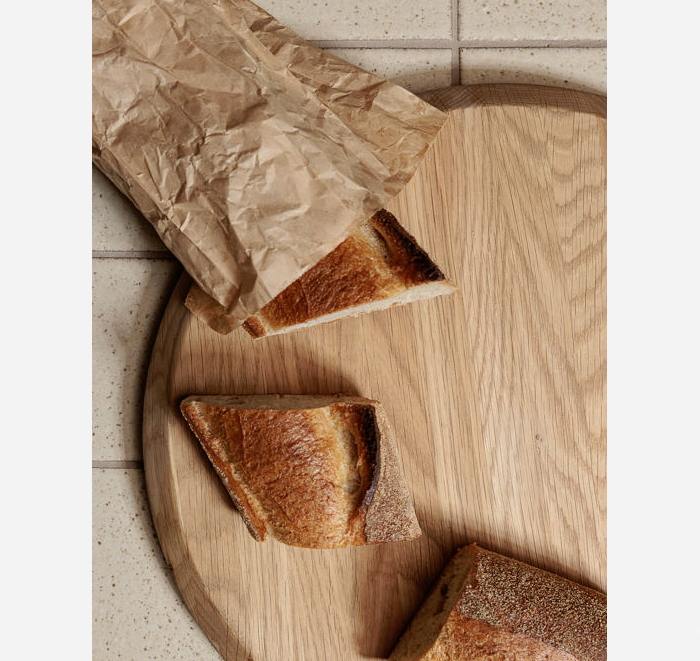 Slices of bread on a wooden cutting board with crumpled brown paper