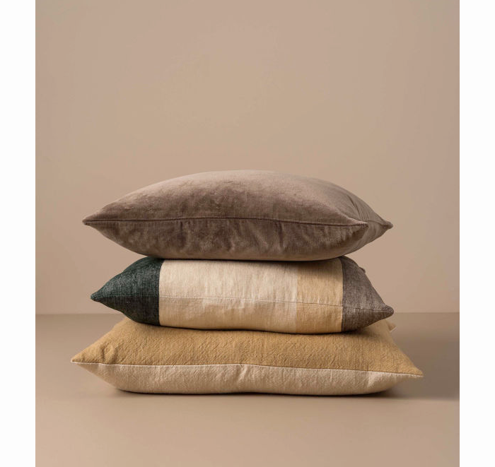 Stack of three textured pillows on a beige background