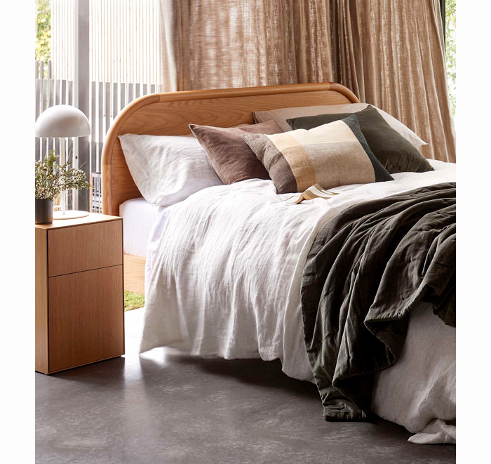 Bedroom with wooden headboard and white bedding, featuring a side table and curtains.