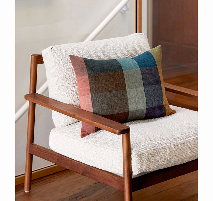 Wooden chair with white cushion and plaid pillow in a room setting