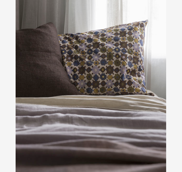 Floral patterned pillow on a bed with neutral bedding