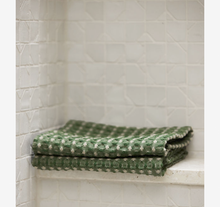 Green patterned towel on a white tiled shelf