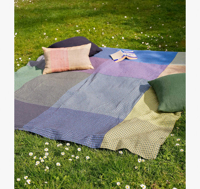 Colorful picnic blanket with pillows on a grassy field