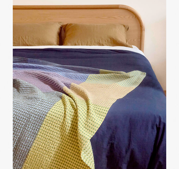 Colorful quilt draped over a bed with wooden headboard