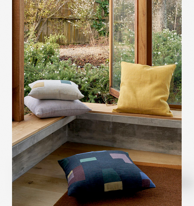 Pillows on a windowsill with a view of greenery outside