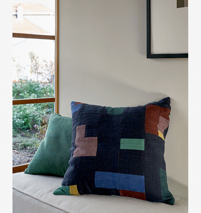 Colorful patchwork pillow on a sofa with a window in the background