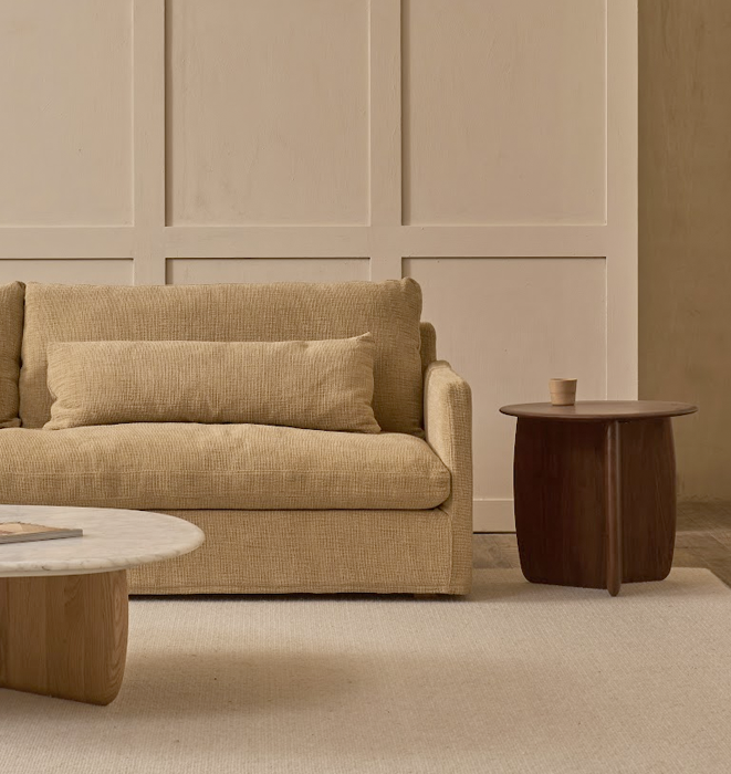 Beige sofa in a living room with a wooden side table and coffee table.