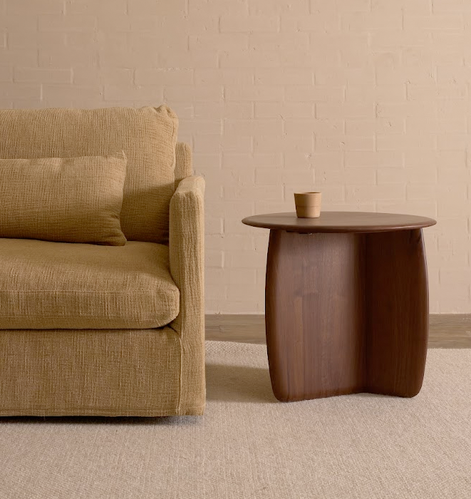 Beige sofa and wooden side table against a beige wall.