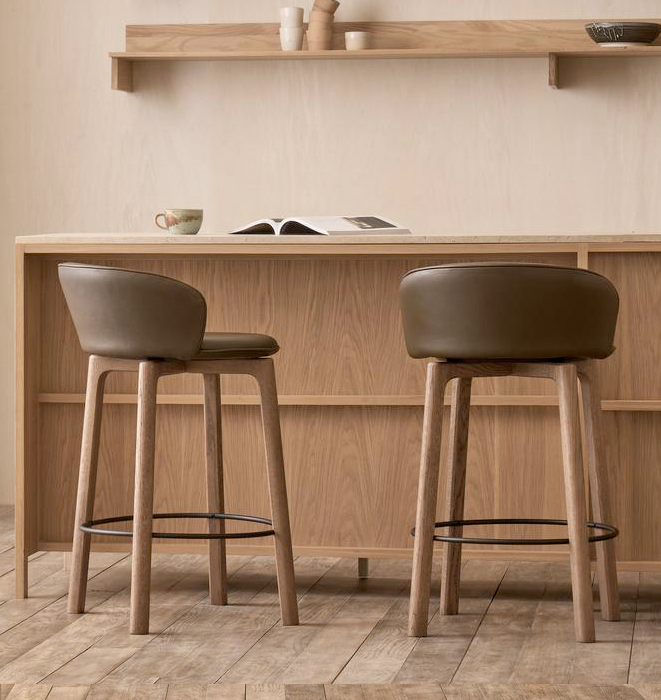 Two brown counter stools in front of a wooden counter with shelves.
