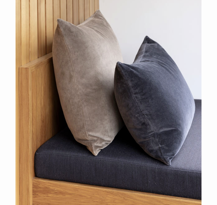 Two pillows on a cushioned bench with wooden sides.