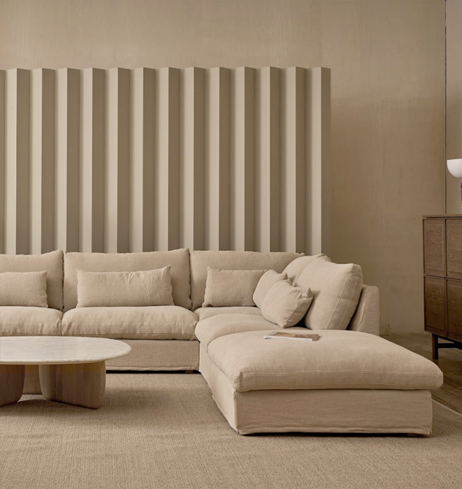 Beige sectional sofa in a modern living room with a striped wall.