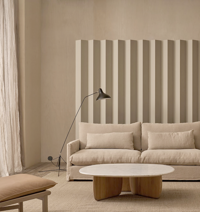 Beige sofa in a living room with a striped wall and a floor lamp.