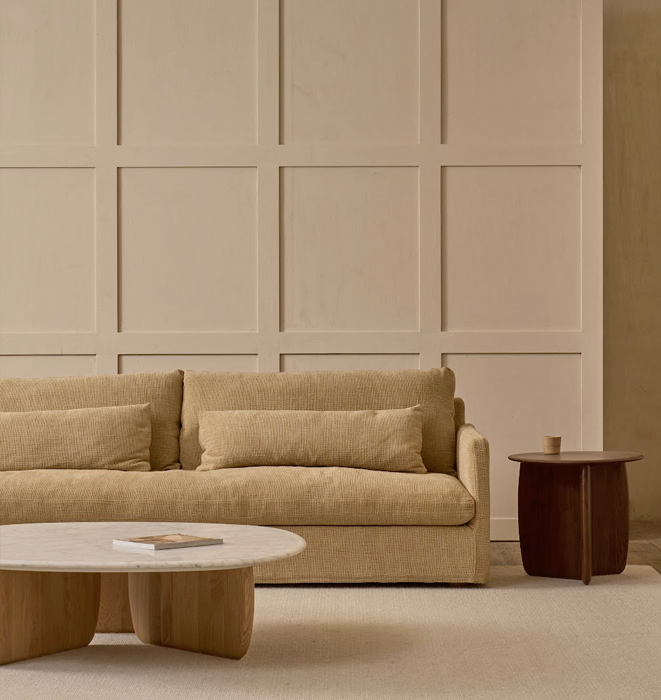 Beige sofa in a room with a textured wall and wooden coffee table.