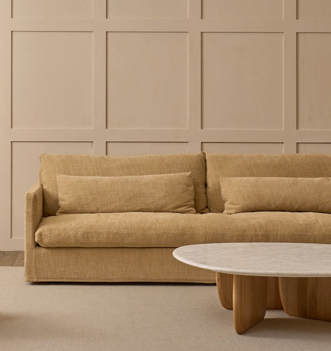 Beige sofa with a matching coffee table against a beige paneled wall.