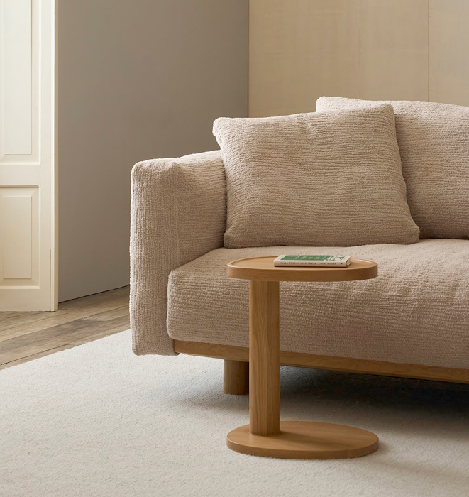 Beige sofa with a wooden side table in a minimalistic living room.