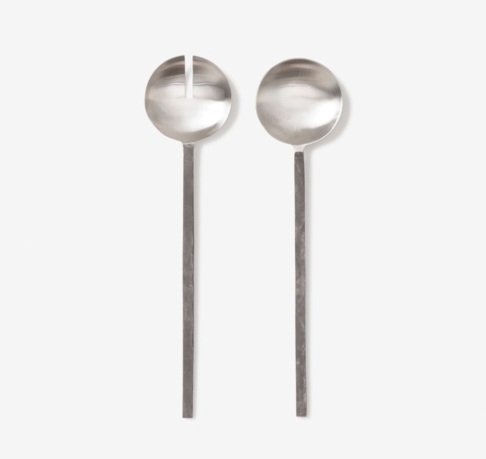 Two stainless steel salad servers on a white background