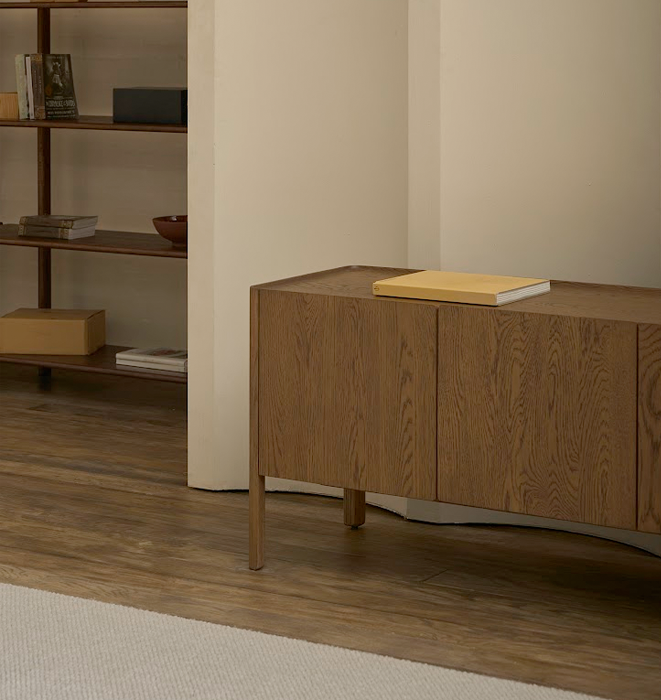 Wooden sideboard in a room with a bookshelf and rug.