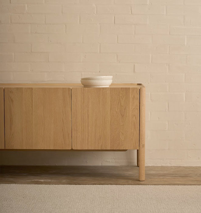 Wooden sideboard with a bowl on a beige brick wall background