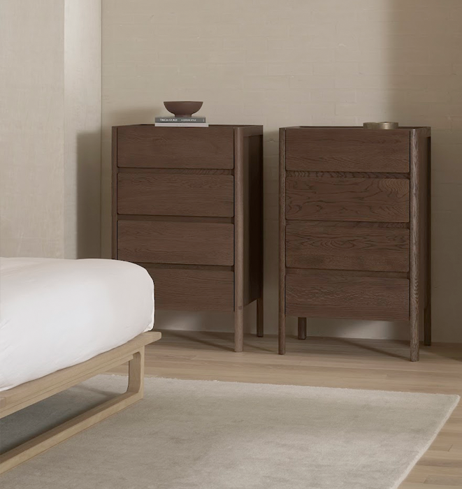 Two wooden drawers with a bed in a minimalistic bedroom setting.