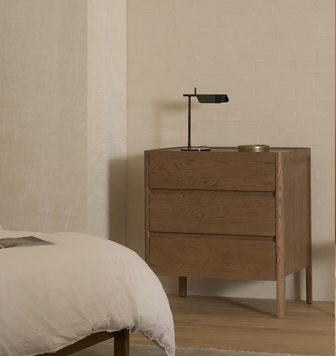 Wooden dresser with a lamp on top in a bedroom setting