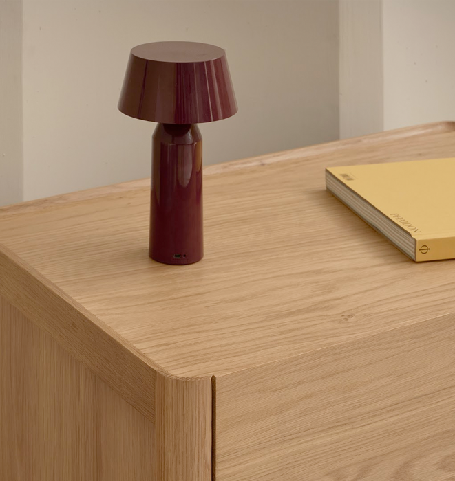 Red table lamp on a wooden surface with a yellow book