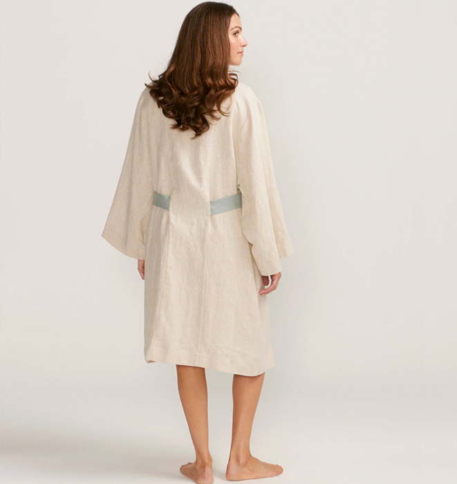 Woman wearing a beige bathrobe on a plain background