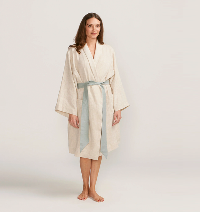 Woman wearing a beige robe with a gray belt on a white background