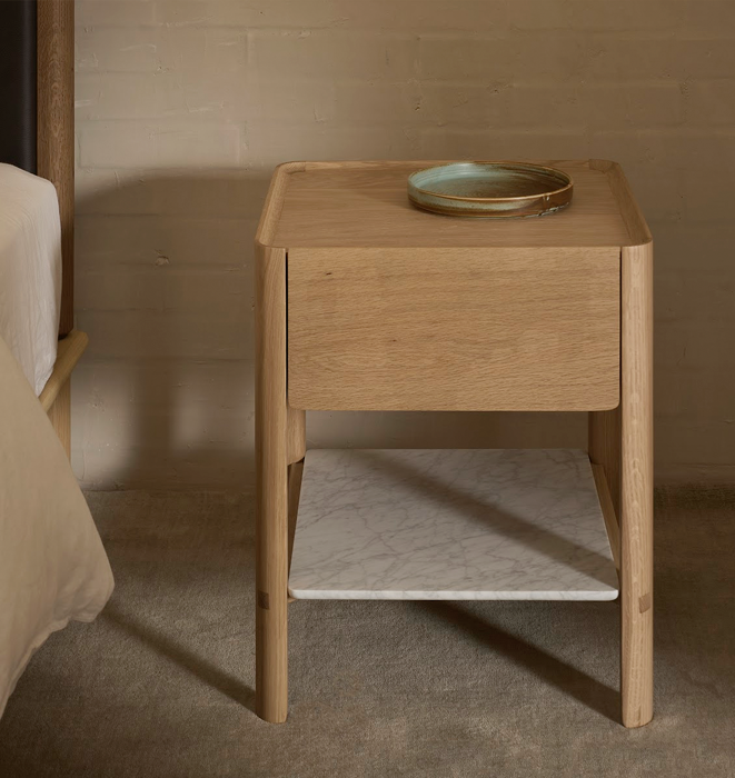 Wooden nightstand with a ceramic plate on top in a bedroom setting