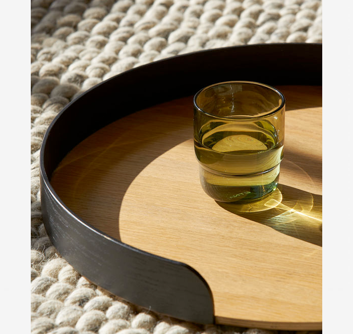 Glass of water on a wooden tray with a textured rug background