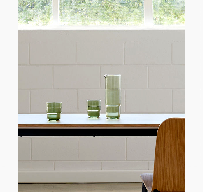 Green glassware on a kitchen counter with a tiled wall and window in the background